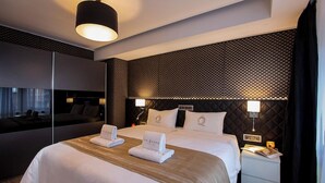 A modern hotel room with a large bed, a bedside table, a nightstand, and a wall-mounted TV. - Carlotta -33 Appartement avec Balcon (Luxembourg)