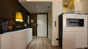 A modern kitchen with a white cabinet, a yellow lamp, and a door with a handle. - Carlotta -33 Appartement avec Balcon (Luxembourg)