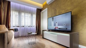 A modern living room with a large flat-screen TV, a sofa, a small round table, and a cabinet.