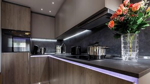 A modern kitchen with a built-in oven, a coffee maker, and a vase with flowers on the counter.