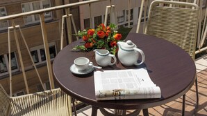 Une table ronde sur laquelle se trouvent un pichet blanc, une tasse blanche, une soucoupe et un bouquet de roses rouges. Un menu est également posé sur la table.