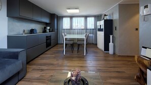 Una cocina moderna con armarios grises, una mesa de comedor con sillas y una cafetera.