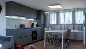 Una cocina moderna con armarios grises, una mesa de comedor con sillas y una cafetera.
