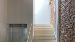 A staircase with a metal elevator door and a brick wall. - Palazzo Maggiore Suite A (Noale)