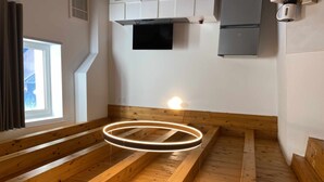 A wooden bench in a room with a window, a wall-mounted television, and a wall-mounted coffee machine. - Palazzo Maggiore Suite A (Noale)