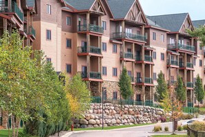 A multi-story hotel with balconies, stone facade, and a stone retaining wall. - 2 Bedroom Deluxe Condo w/ Kitchen, Sleeps 8, Waterpark, Glacier Canyon Resort!! (Baraboo)