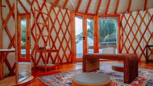 A yurt interior with a round seating area, a wooden bench, and a patterned rug. - Nomad Yurts (Coron)