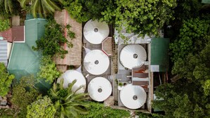 A rooftop with multiple satellite dishes, surrounded by dense greenery and a corrugated metal structure. - Nomad Yurts (Coron)