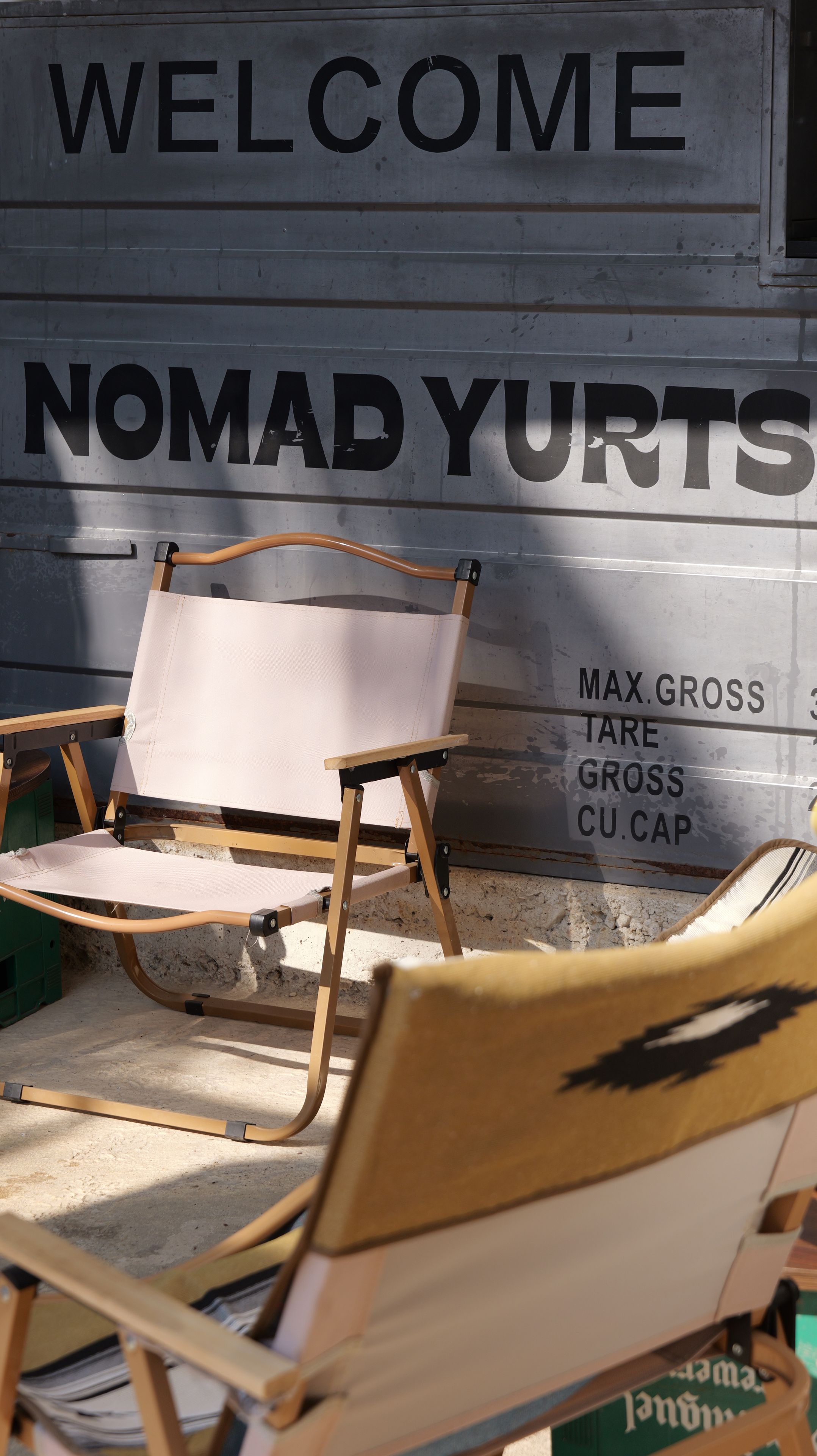 A sign with 'WELCOME NOMAD YURTS' and a chair in front of it.