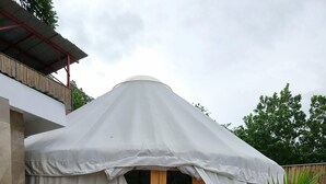 A tent-like structure with a wooden door and a 'Welcome' mat at the entrance. - Nomad Yurts (Coron)