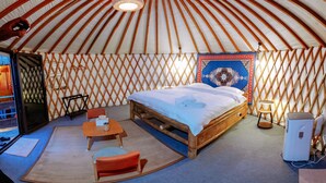 A yurt with a bed, a table, and a chair. - Nomad Yurts (Coron)