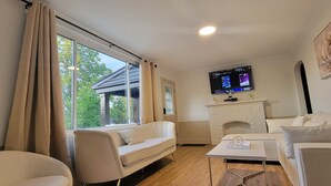 Moderni olohuone, jossa on sohva, pöytä, takka ja seinälle asennettu televisio.