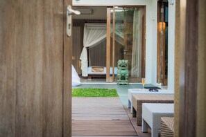 Relax in a serene room with a comfortable bed, mosquito net, and a glass of wine on the table.