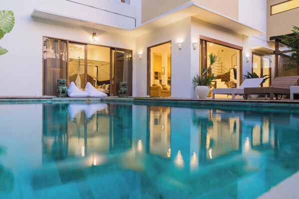 Relax by the pool in a spacious living area with multiple rooms and outdoor furniture.
