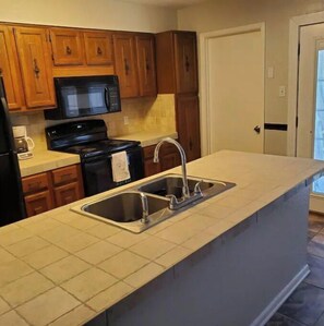 Fully equipped kitchen with a large island, double sink, and modern appliances.