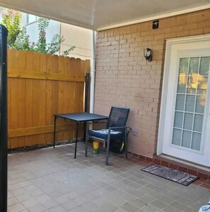 Enjoy a quiet moment on the patio with a table and chair, surrounded by a brick wall and a door with a window.