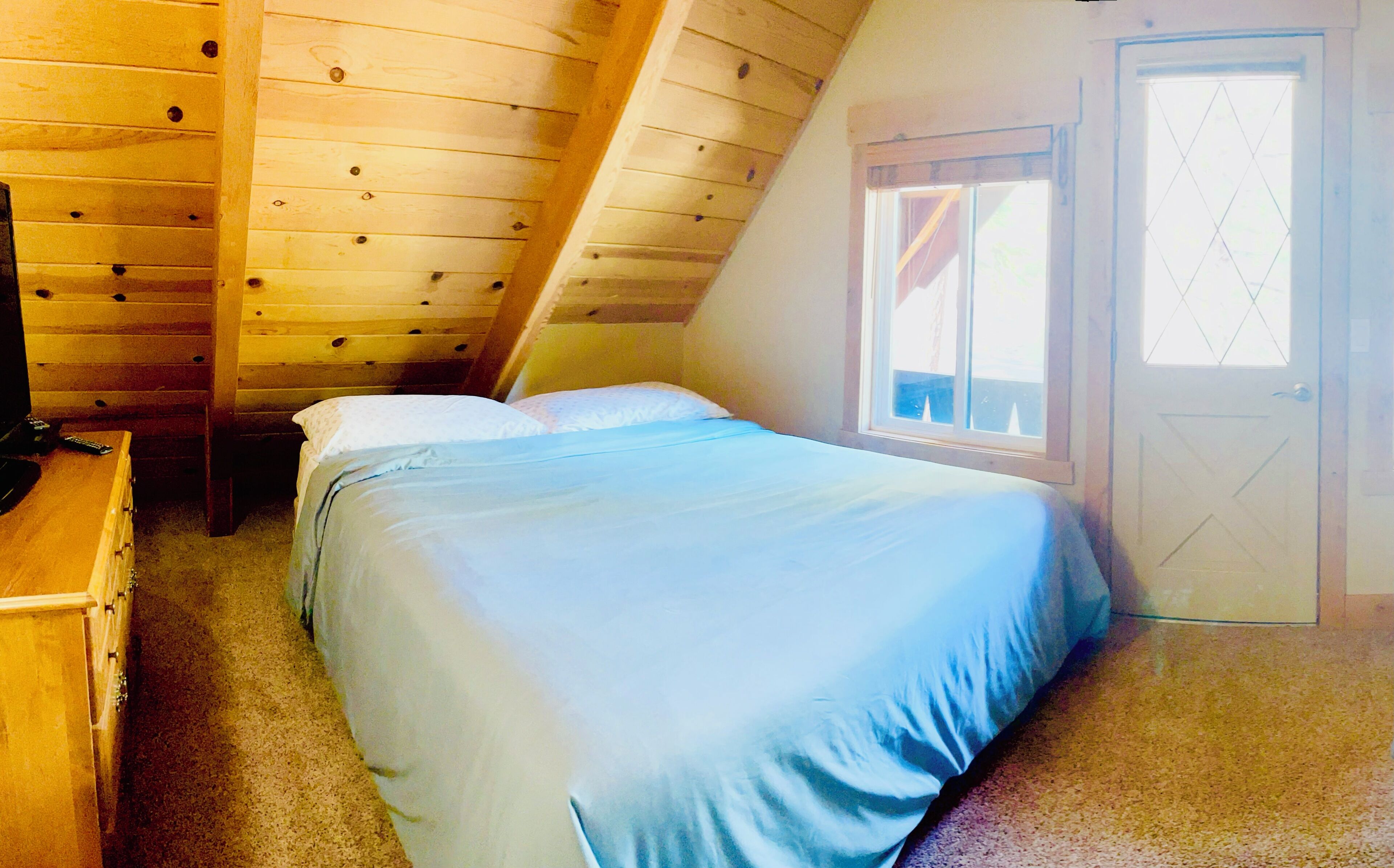 Une chambre avec un lit simple, une commode en bois et une fenêtre donnant sur l’extérieur.