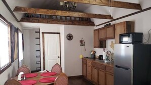 Une cuisine avec des meubles de rangement en bois, un réfrigérateur et une table à manger avec des chaises.