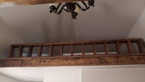 Une pièce de style loft avec des poutres en bois apparentes, une échelle en bois, un ventilateur de plafond et une décoration murale en forme d’étoile.