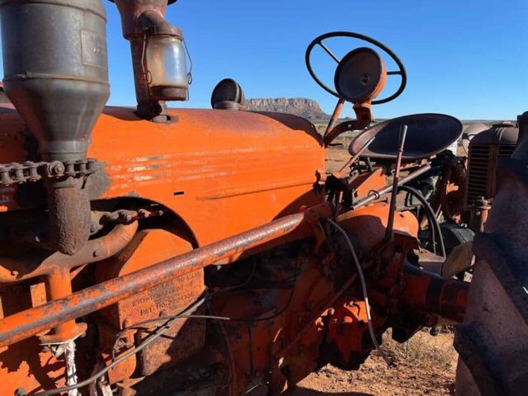 A vintage orange tractor with visible mechanical components and a steering wheel.