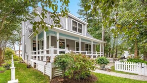 A two-story house with a porch, surrounded by a white picket fence and lush greenery. - Waterfront Home & Golf Getaway - Close to the Boardwalk and Assateague (Berlin)