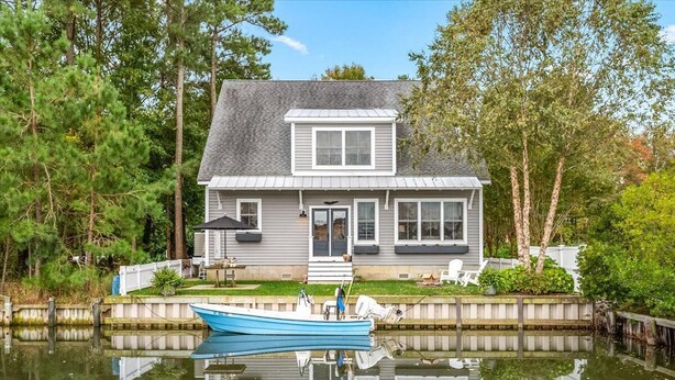 A house with a dock and a boat, surrounded by trees and a calm body of water. - Waterfront Home & Golf Getaway - Close to the Boardwalk and Assateague (Berlin)