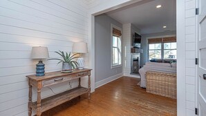 A hallway with wooden flooring, a rustic wooden console table with lamps, a potted plant, and a wicker basket. - Waterfront Home & Golf Getaway - Close to the Boardwalk and Assateague (Berlin)