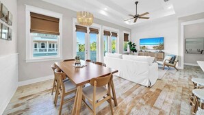 A spacious living area with a dining table, white sofa, and a ceiling fan.