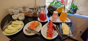 A breakfast buffet with various fruits, juices, and cereal options.
