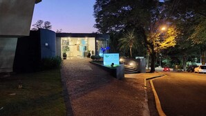 Una entrada de hotel moderna con fachada de vidrio, un sendero bien iluminado y un cartel.