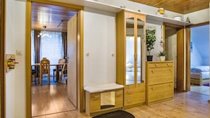 A room with a wooden wardrobe, a bench, a bed, a small table, and a chair. - Holiday flat "am Talsee", with lake view, balcony and Wifi (Unterkirnach)