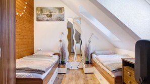 Ein Schlafzimmer mit zwei Betten, Holzboden, einem Bild an der Wand und einem Spiegel.