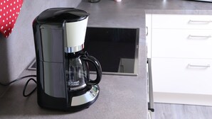 Une cuisine équipée d’une machine à café, d’un four à micro-ondes et de placards.