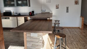 A kitchen with a wooden island, bar stools, a coffee machine, and a microwave. - Apartment "1 Bartölke" with Private Terrace & Wi-Fi (Bockenem)