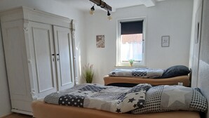 A bedroom with two beds, a wardrobe, a window with a view, and a small plant. - Apartment "1 Bartölke" with Private Terrace & Wi-Fi (Bockenem)