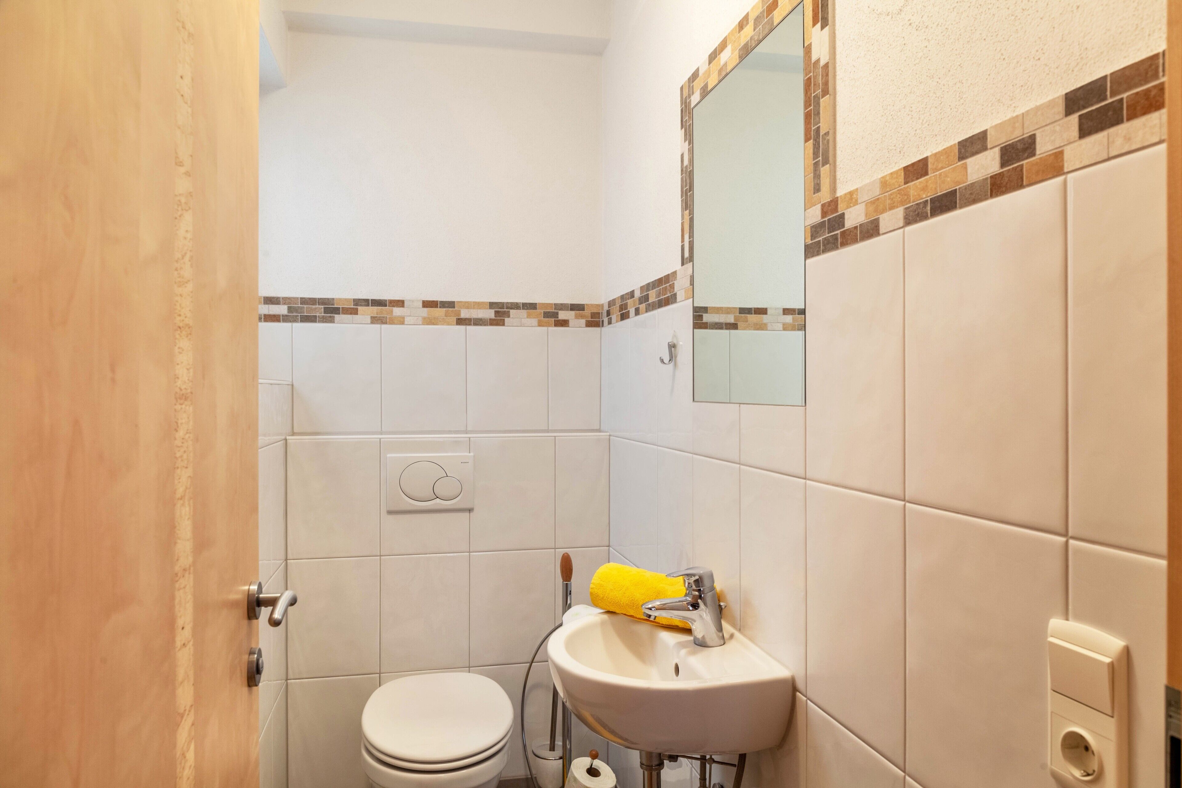 Ein Badezimmer mit Toilette, Waschbecken, Spiegel und Handtuchhalter.