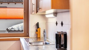 Une cuisine avec une fenêtre, un évier, une machine à café et un bloc à couteaux.