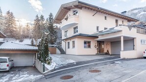 Un immeuble à plusieurs étages doté d’un garage, d’une allée couverte et surplombant un paysage enneigé.
