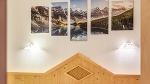 Une chambre à coucher avec une tête de lit en bois, un lit recouvert d’une literie à motifs et trois photographies encadrées représentant des paysages, accrochées au mur.