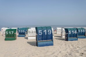 Beach chairs with numbers on them, arranged on a sandy beach. - Holiday Apartment 'Nordsee' with Shared Terrace, Shared Garden & Wi-Fi (Hooksiel)