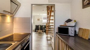 A kitchen with a stove, microwave, and wooden ladder. - Holiday Apartment 'Nordsee' with Shared Terrace, Shared Garden & Wi-Fi (Hooksiel)