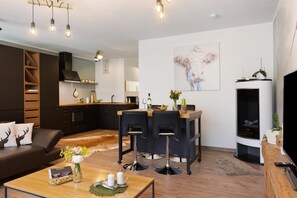 Un salon moderne comprenant un canapé, une table basse et un coin repas avec des tabourets de bar.