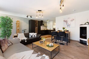Un salon moderne avec un canapé, une table basse et un coin cuisine à l’arrière-plan.