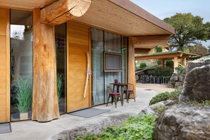 A wooden building with large glass doors, a table with chairs, and a bicycle.