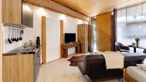 Una cucina moderna con piano cottura integrato, soffitto in legno e una TV a schermo piatto su un supporto in legno.