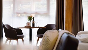 Una stanza con un letto, un tavolo da pranzo con sedie, una bottiglia di vino e un vaso con fiori.