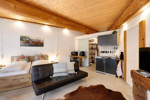 A modern interior with a sofa, a wooden ceiling, a kitchen area, and a dining table.