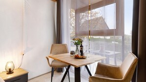 Una habitación moderna con una mesa de madera, dos sillas, un florero con flores y vistas amplias a través de grandes ventanas.