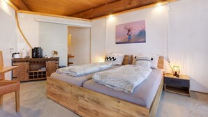 Una habitación con estructura de madera, con una cama, un escritorio y un cuadro en la pared.
