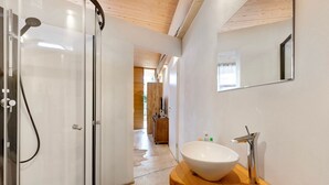 Une salle de bain moderne avec une douche à l’italienne en verre, un meuble-lavabo en bois avec un vasque blanche et un miroir au mur.